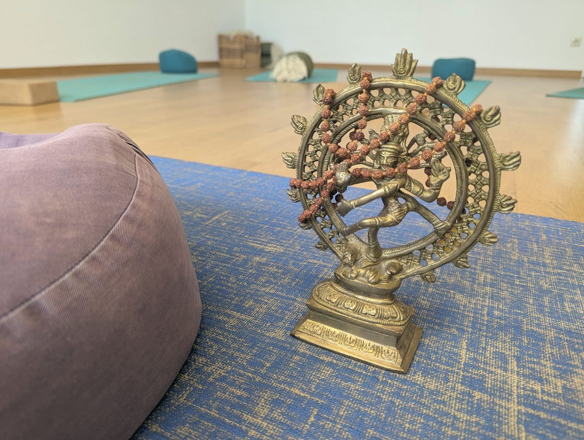 Brass Nataraja statue with a mala on a blue mat