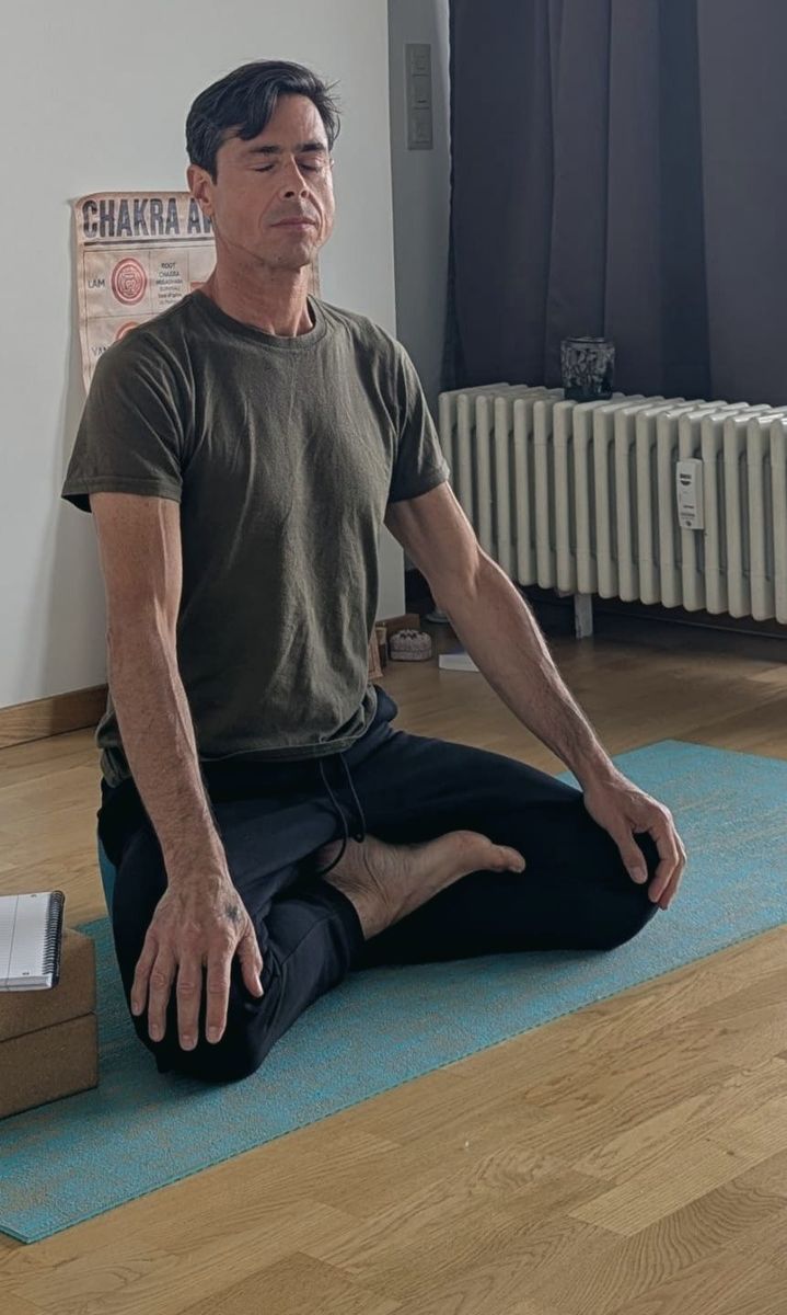 Gustavo meditating on a teal mat in the studio, eyes closed